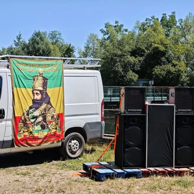 Le sound system Illwood en extérieur : enceintes à côté d'un utilitaire portant une bannière reggae